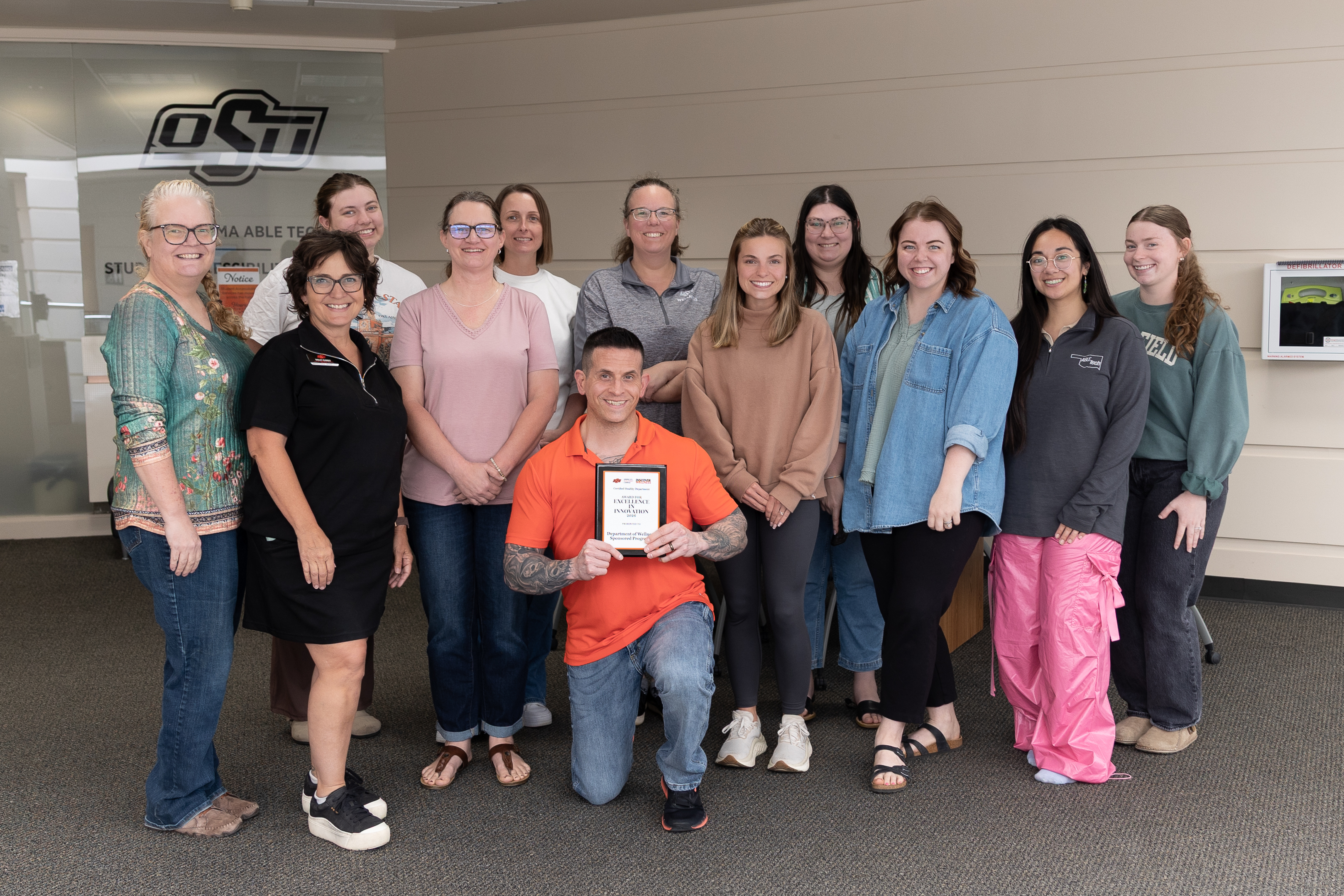 A group image of the Department of Wellness Sponsored Programs posing together with their award plaque. 