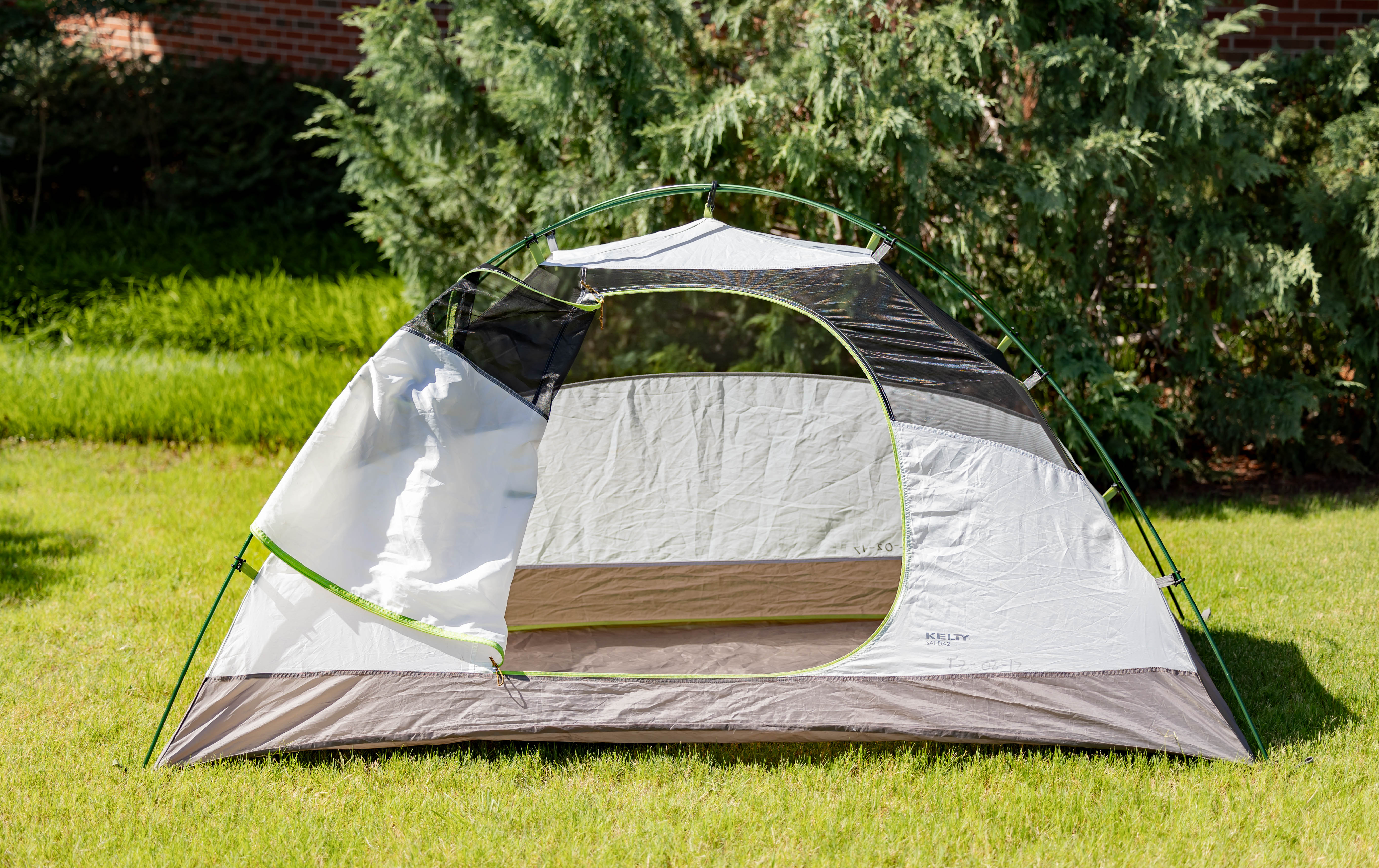 A decorative image of one of the tents that is available for rent. The tent is in a green field with a tree in the background and the door to the tent is open.