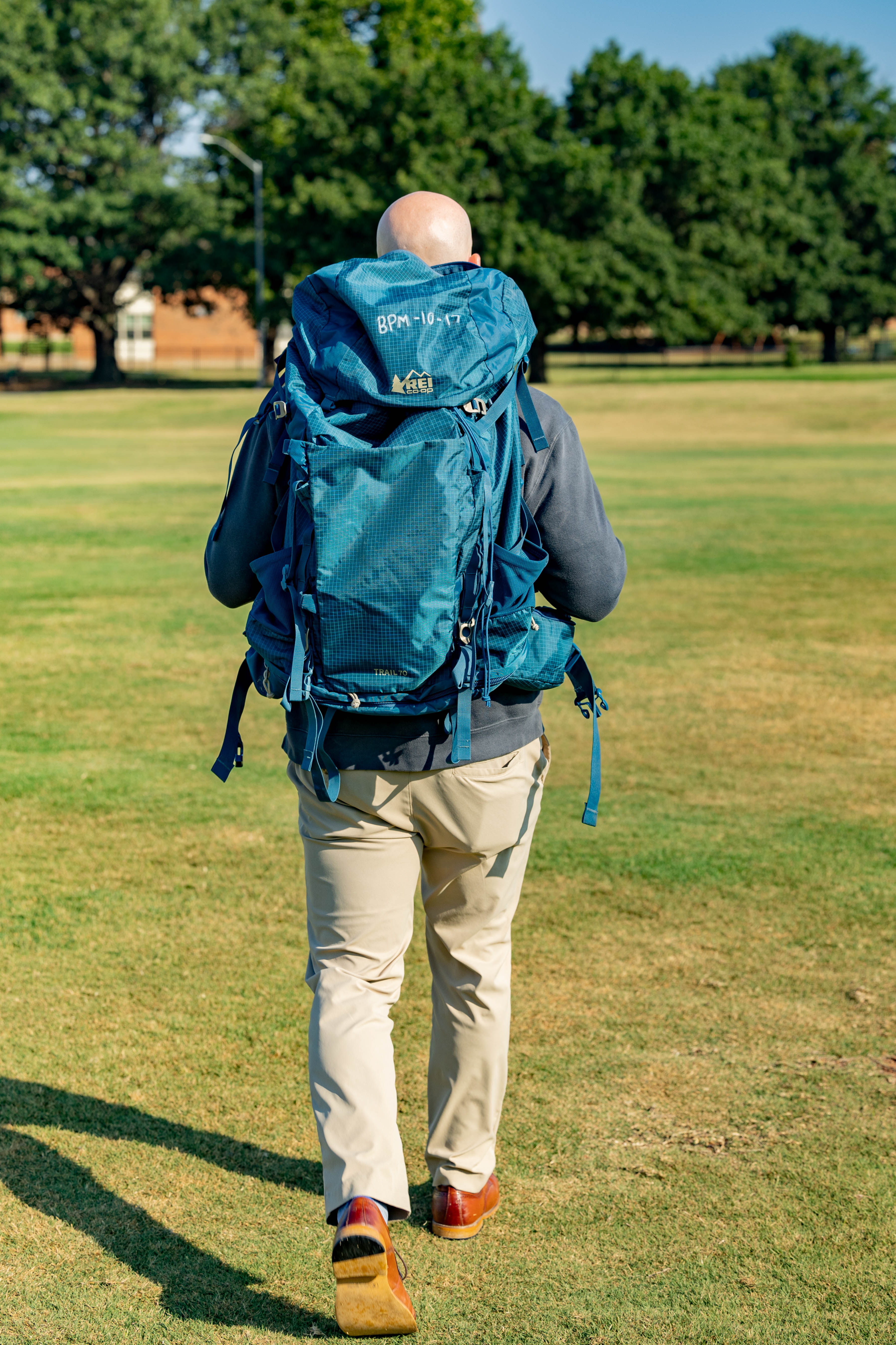 A decorative image of a man walking in a field with one of the backpacks available for rent. 