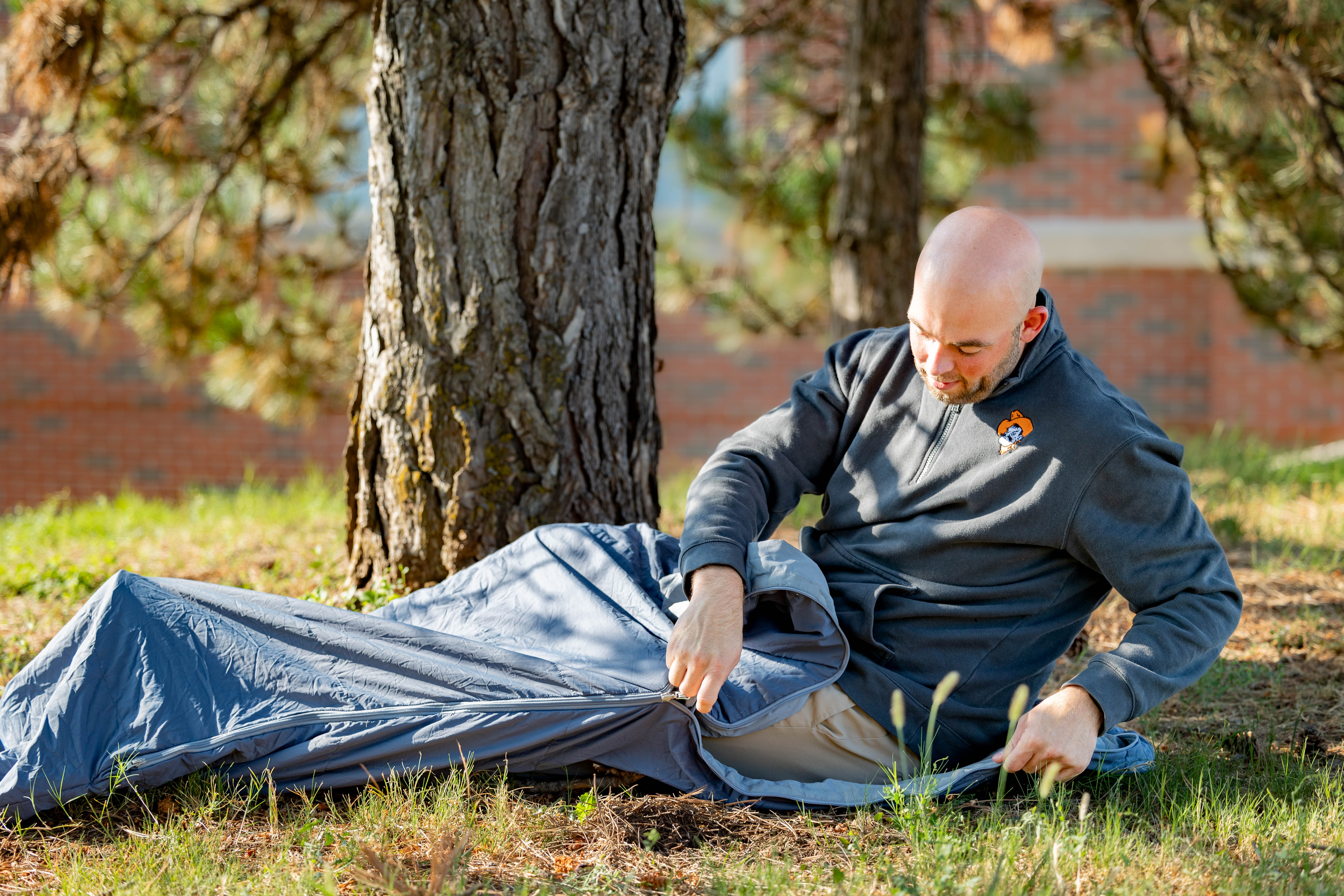 A man zipping up one of the sleeping bags available for rent. 