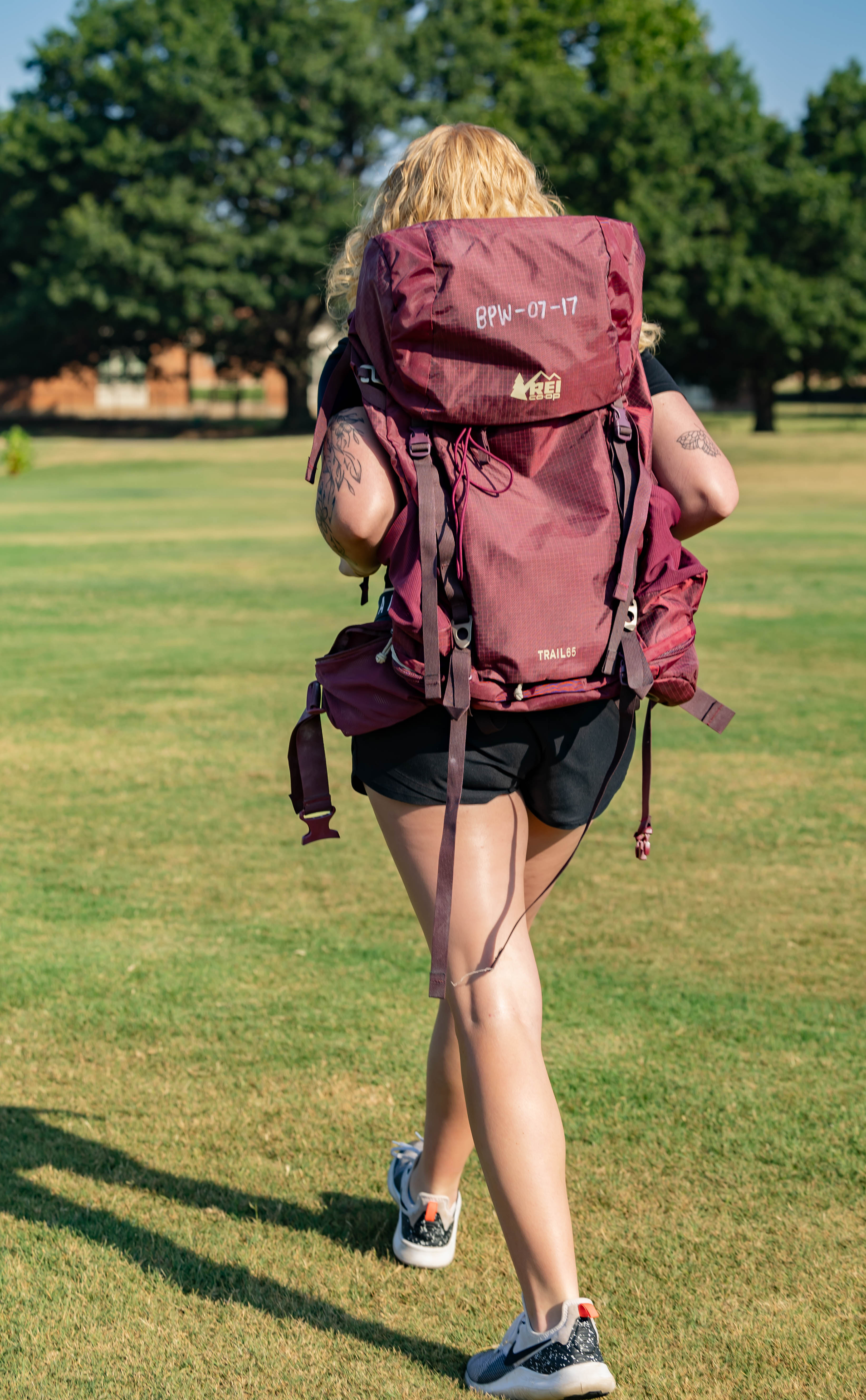 A decorative image of a woman walking while carrying one of the backpacks available for rent. 
