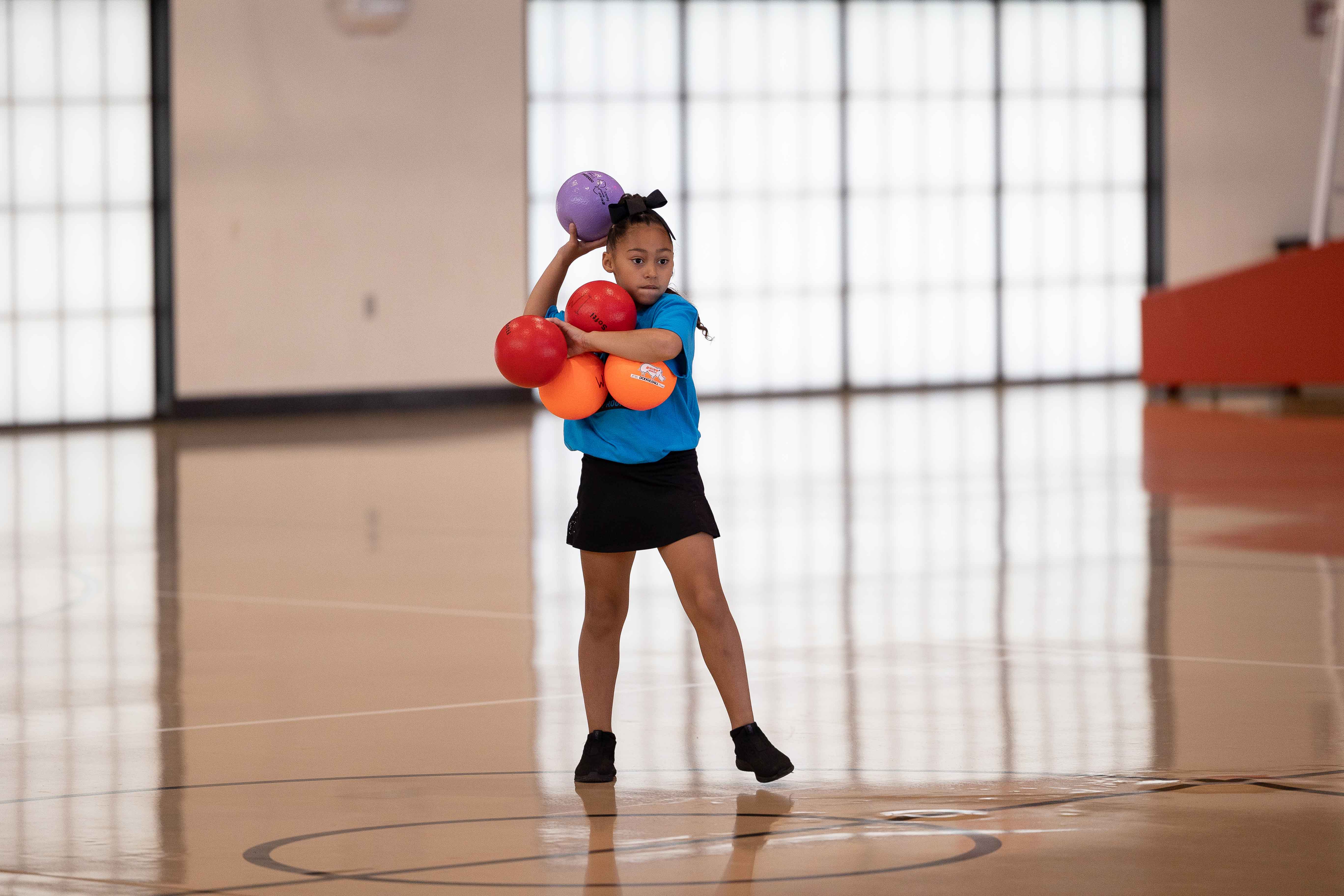 A little girl throwing dodgeball
